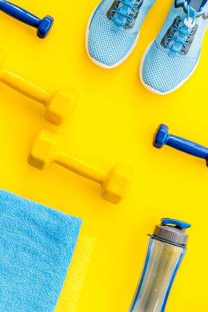 Athletics flat-lay with dumbbells, towel, sneakers on yellow background top-downの写真素材
