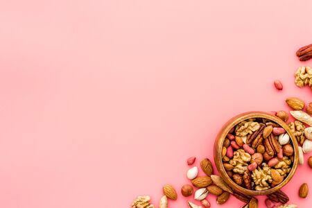Mixed nuts in bowl - healthy snack - on pink background top-down frame copy spaceの写真素材