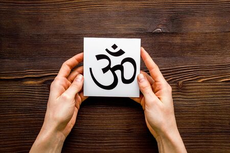 Om - Buddhist inner peace symbol - in hands on wooden desk top viewの写真素材