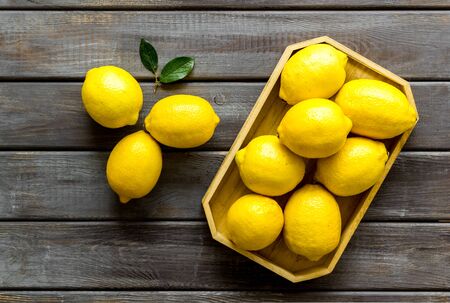 Ripe lemons in tray on dark wooden backgroud top-down.の写真素材