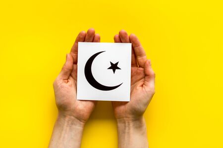 Islam sybmbol crescent and star in hands on yellow table top viewの写真素材