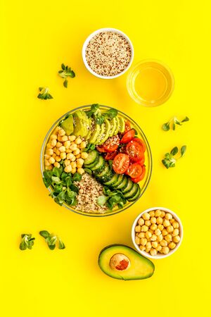 Healthy salad bowl with quinoa, avocado and chickpeas on yellow background top-down.の写真素材
