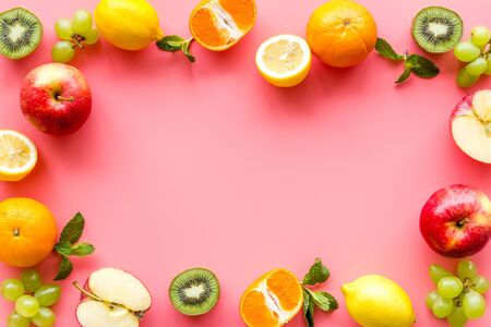 Oranges, lemon, apple, kiwi and grape - healthy food concept with fruits - on pink background top-down.の写真素材