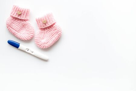 Positive pregnancy test. Baby girl concept with pink booties on white background top-down copy spaceの写真素材