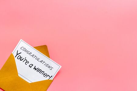 Youre a winner. Envelope with congratulation card on pink table top view copy spaceの写真素材