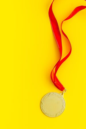Gold medal with red ribbon - winner, success concept - on yellow background top view copy spaceの写真素材