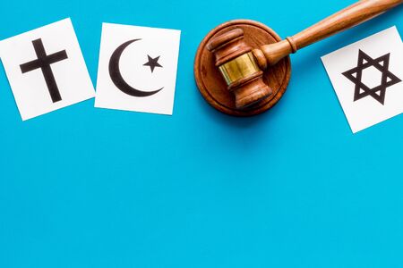 Religious conflict concept. World religions symbols near gavel on blue background top view copy...
