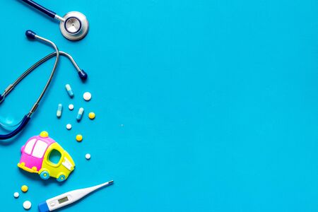 Flu treatment for children. Pills, thermometer, stethoscope and toys on blue background top view copy spaceの写真素材