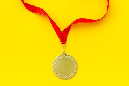 Gold medal with red ribbon - winner, success concept - on yellow background top viewの写真素材