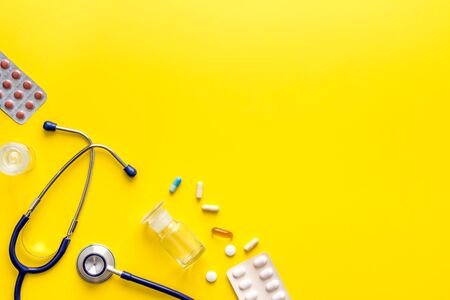 Pills, stethoscope - cold, flu and virus treatment. on yellow desk from above space for textの写真素材
