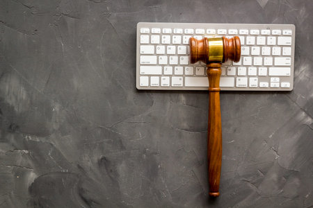 Judge hammer, keyboard on grey lawyer's desk top view.