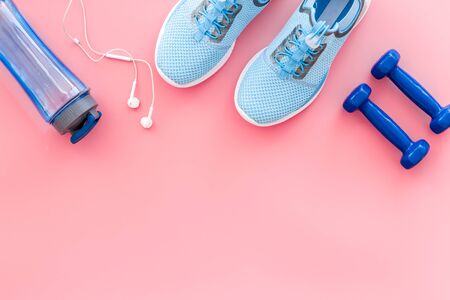 Sport background with sneakers and dumbbells on pink table top view.の写真素材