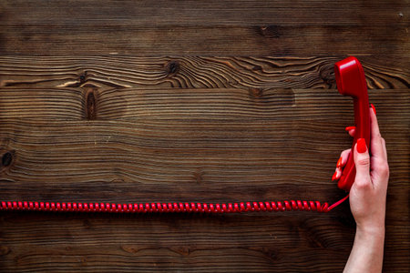 landline telephone receiver in hand on wooden background top view copy space