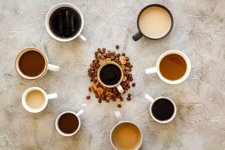 Cups of hot drinks on beige desk top view.の写真素材