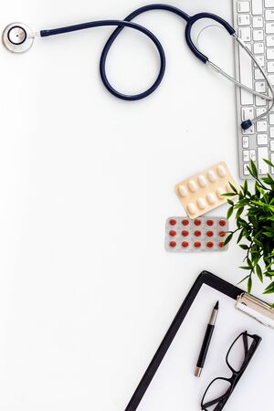 Doctor office table with pills and stethoscope. White background top-down.の写真素材