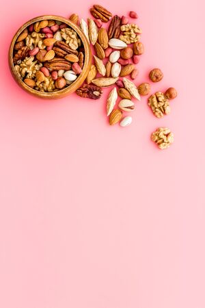 Mixed nuts in bowl on pink background top-down frame copy spaceの写真素材