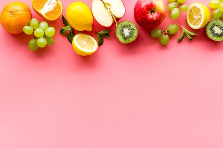 Fresh fruits background with citruses, apple, kiwi and grape on pink table top-down frame copy spaceの写真素材