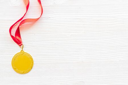 Gold medal with red ribbon - winner, success concept - on white wooden background top view copy...