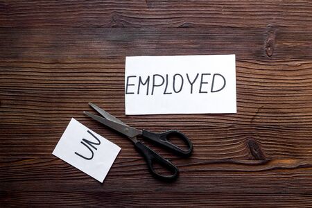 Employment, new job concept. Torn paper sheet - unemployed - sciccors on wooden table top-down.の写真素材