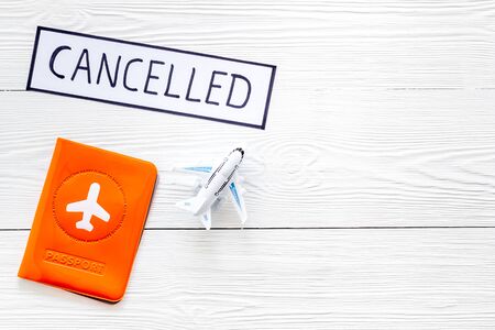 Cancelled flight. Airplane and passport on white wooden background top view copy spaceの写真素材