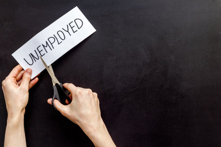 Employment, new job concept. Hands cut paper -unemployed - on black desk from above copy space