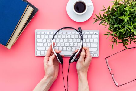 Education online school concept. Headphones in hands, pink desk with computer top view.の写真素材