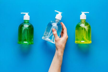 Sanitizer bottle in hands - coronavirus prevention - on blue background top viewの写真素材
