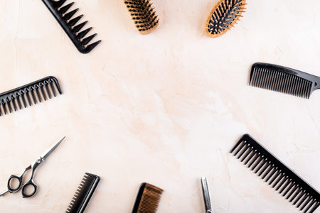 Hairdressing equipment. Combs, scissors on beige desk top-down.