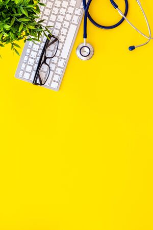 Stethoscope on doctor office desk. Yellow background top view space for textの写真素材