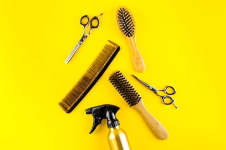 Hairdressing instruments. Combs, scissors and spray on yellow desk from above frame space for textの写真素材