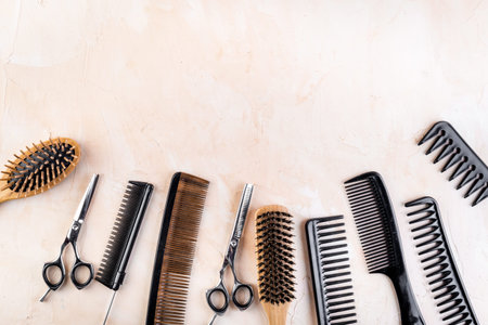Combs, hairbrush, scissors - hairdresser eqiupment - on beige table top-down.の写真素材