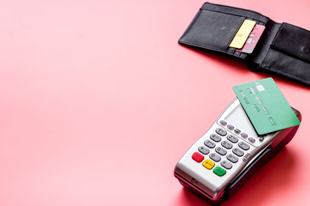 Payment by credit card. Terminal on pink desk copy space