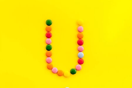 Letter U - alphabet made with sweets on yellow from above.の写真素材