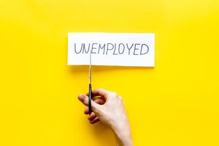 Employment, new job concept. Hands cut paper -unemployed - on yellow desk from aboveの写真素材