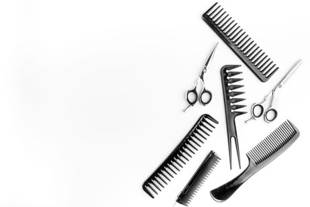 Combs, hairbrush, scissors on white desk from above.