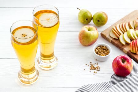 Glasses of beer with apple and peer on white wooden deskの写真素材