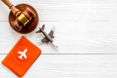 Flight cancellation. Airplane, passport, judge gavel on white wooden desk top-down copy spaceの写真素材