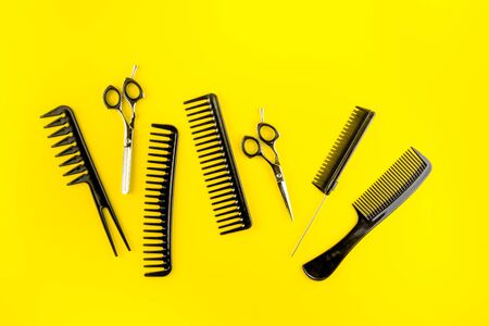 Combs, hairbrush, scissors - hairdresser eqiupment - on yellow table top-downの写真素材