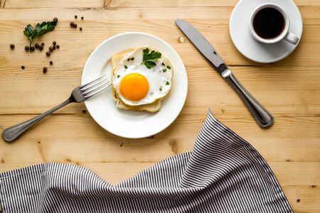 Fried eggs sandwich on plate - light wooden dinner table top viewの写真素材