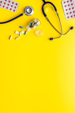 Flu treatment - pills and stethoscope on yellow table top view copy spaceの写真素材