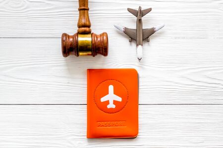 Flight cancellation. Airplane, passport, judge gavel on white wooden desk top-downの写真素材