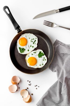 Fried eggs on frying pan on white desk top-downの写真素材
