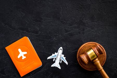 Flight cancellation. Airplane, passport, judge gavel on black desk top-down copy space