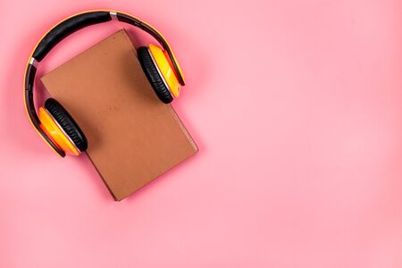 Book and yellow headphones on. Pink background top view copy spaceの写真素材