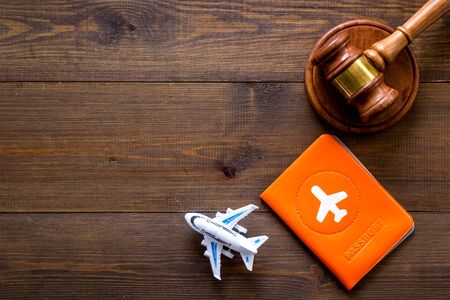 Flight cancellation. Airplane, passport, judge gavel on wooden desk top-down copy spaceの写真素材