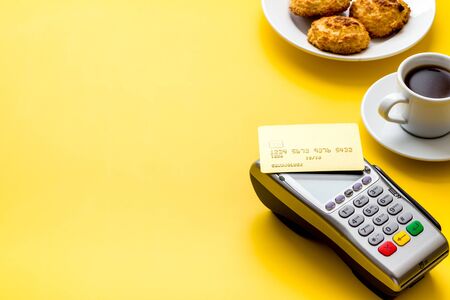 Payment transactions. Terminal and credit card on cafe yellow table copy spaceの写真素材