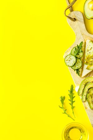 frame of avocado sandwiches on yellow kitchen table top view copy spaceの写真素材