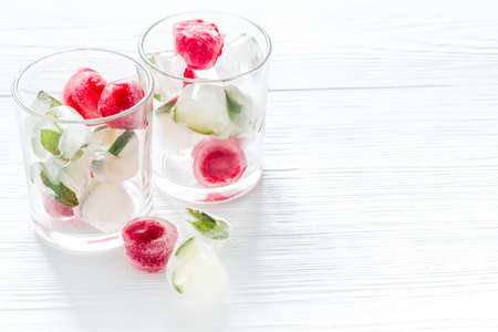 Cocktail glasses with berries in ice cubes on white table.の写真素材