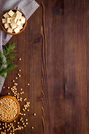 Tofu cubes in bowl and soybeans on wooden desk from above copy spaceの写真素材