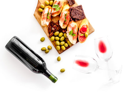 Red wine and snacks set on cutting board top view.